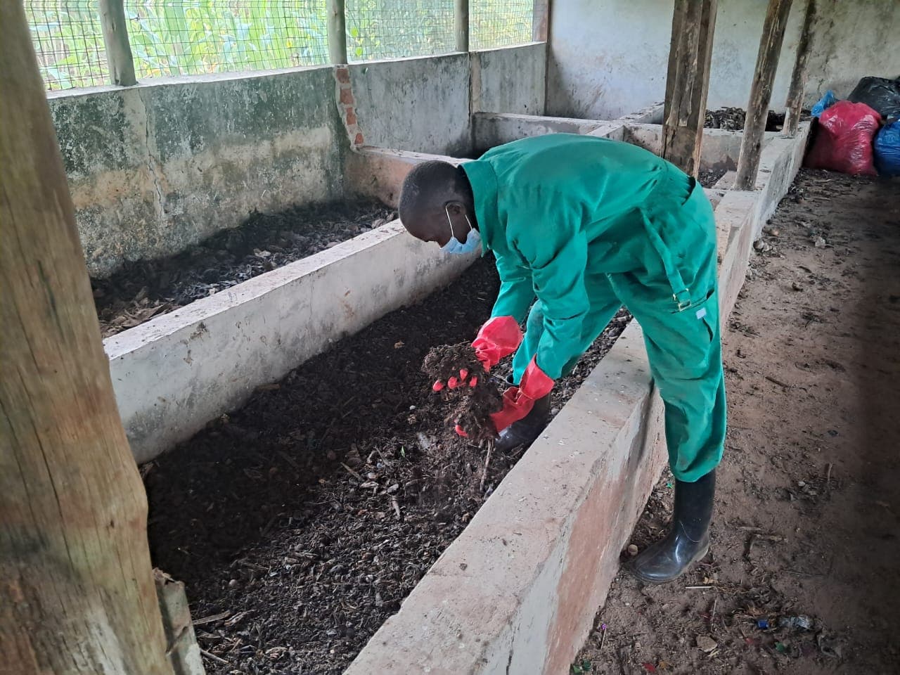 RERU worker turning organic waste in a composting bay