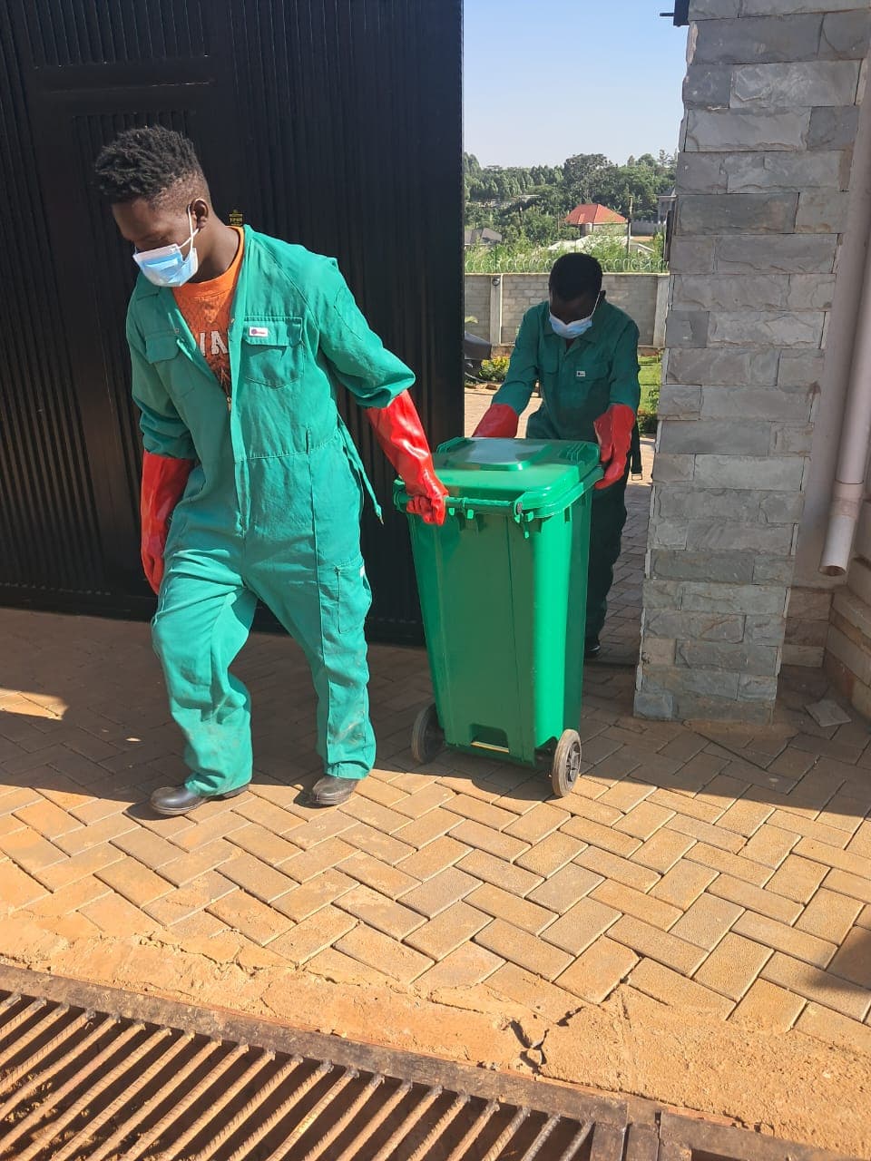 RERU crew wheeling a collection bin from a household gate